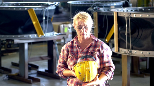 在金属制造厂工作的成熟女人，戴安全帽视频素材
