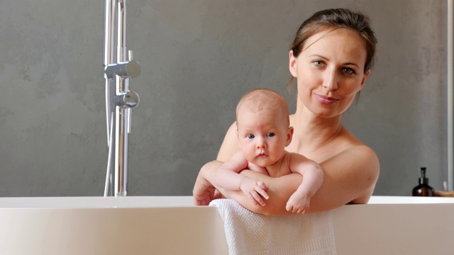 母亲和她刚出生的孩子在一个现代化的浴室里视频下载