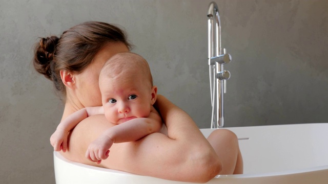 母亲和她刚出生的孩子在一个现代化的浴室里视频下载