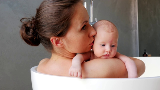 母亲和她刚出生的孩子在一个现代化的浴室里视频素材