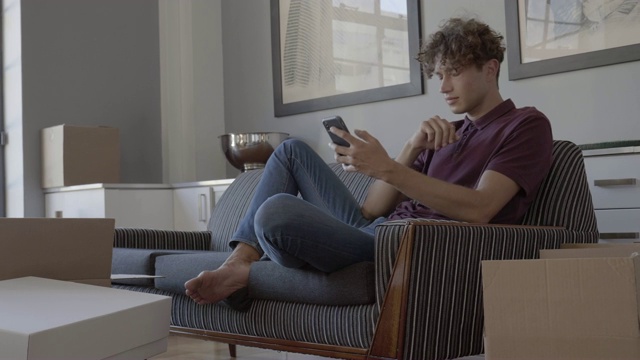 年轻的男性博主在沙发上使用手机视频素材