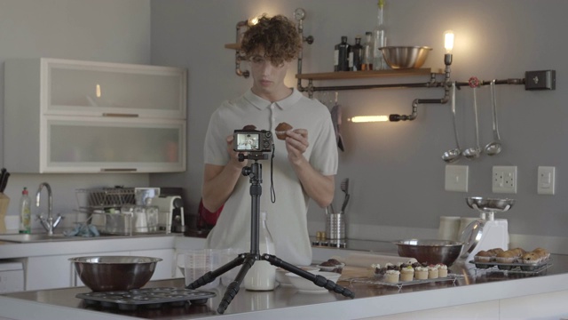 年轻的男性影响者为做松饼制作视频博客视频素材