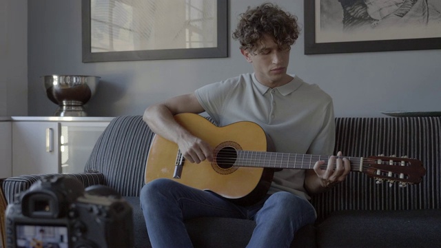 男性影响者一边弹吉他一边做视频博客视频素材