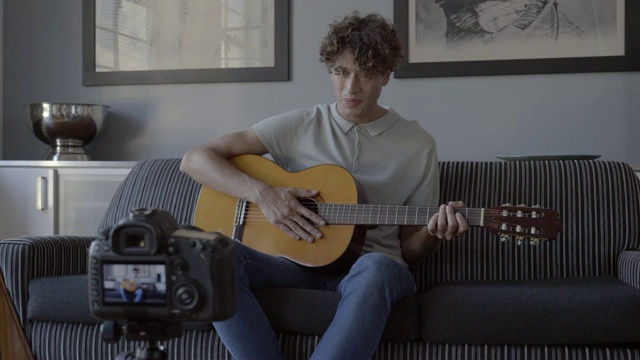 男性影响者一边弹吉他一边制作视频教程视频素材