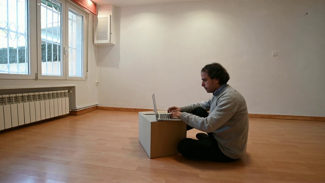 一个人在一个空屋子里的纸板箱上打字。移动视频下载