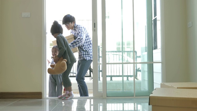 亚洲家庭搬到新家，打开门和孩子跑进房子视频素材