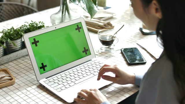 一个女人的手在咖啡馆笔记本电脑的绿色屏幕上工作的特写视频素材