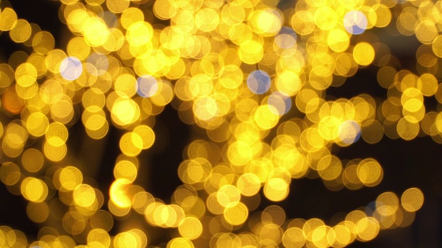 抽象模糊的金色散景灯花环背景在夜晚。圣诞节和新年假期的背景。视频素材
