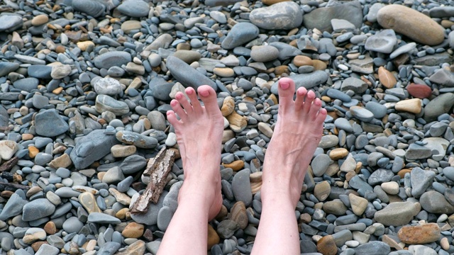 女人的脚在石滩上拍打着大海。视频下载