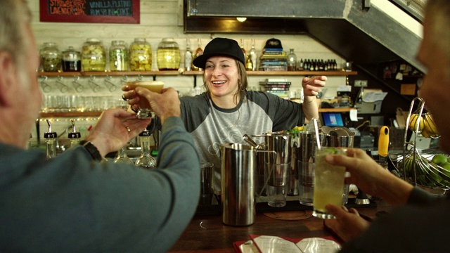 一个白种女调酒师在她三十多岁的双手微笑两个白种男人在酒吧工作时他们的鸡尾酒视频下载