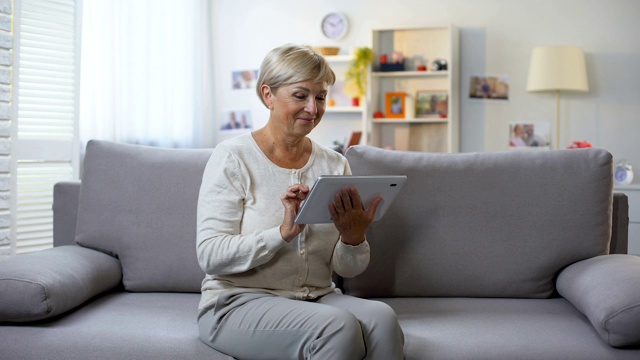 退休女性滚动平板电脑应用程序在家放松，网上购物视频素材