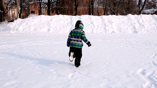 男孩在雪里玩。跑着爬上高高的雪堆。视频下载