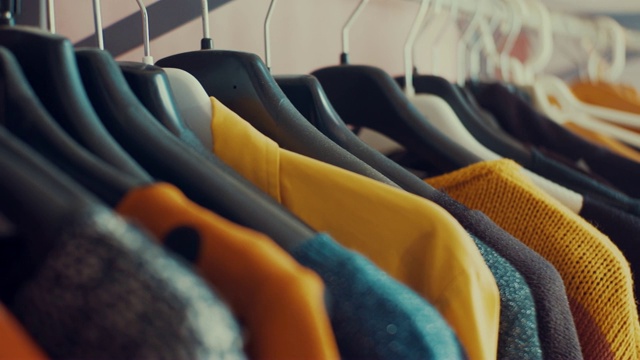 摄影小车拍摄了商店里五颜六色衣服的衣柜衣架。彩色的衣服挂在衣架上视频素材