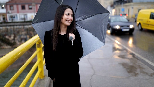 年轻女子撑着伞走在桥上视频下载