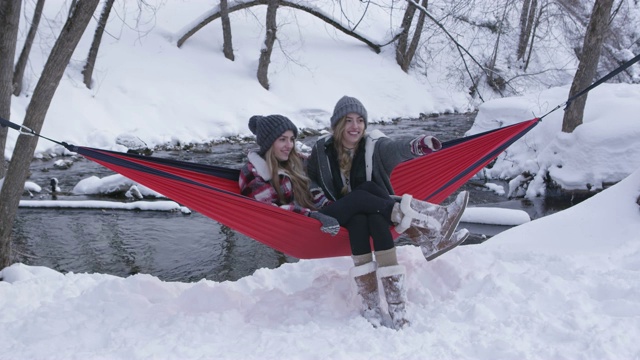 一对双胞胎姐妹坐在外面的雪地里，在吊床上聊天视频下载