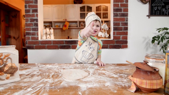 小男孩在厨房做饭，竖起大拇指。视频素材