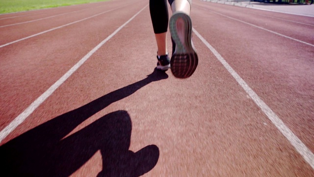 近距离的脚，不认识的女运动员跑在轨道上的慢动作视频下载