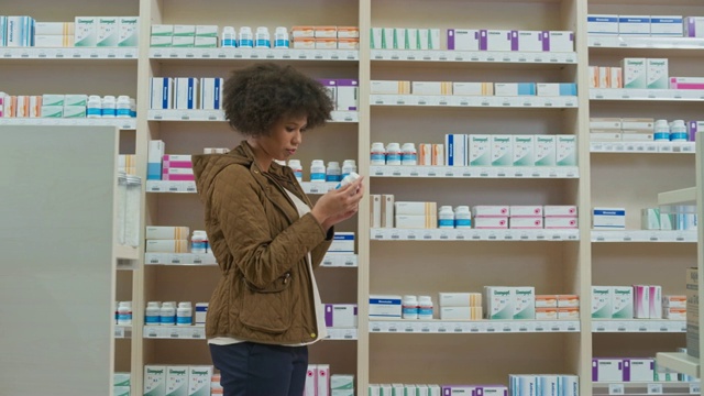 一名年轻女子在药店里读着药瓶背面的标签，然后走开了视频素材