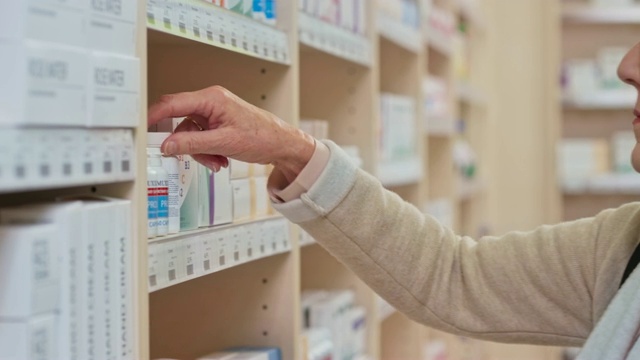 年长的女士在检查她从药店货架上拿下来的药瓶视频素材