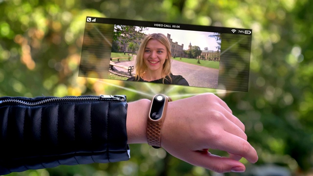 在全息图中出现的女人的手叫朋友。智能手表未来和科技。背景是绿树。视频下载
