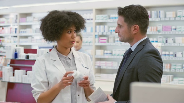 女销售员在药店建议一个商人关于维生素补充剂视频素材