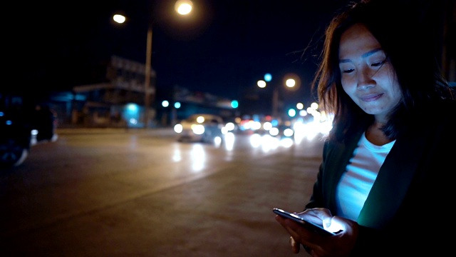 亚洲女人在夜路边玩智能手机视频素材