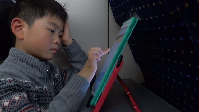 聪明的男孩在高铁上使用数字平板电脑视频素材