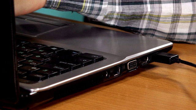 手连接黑色USB线到笔记本电脑。特写镜头视频素材