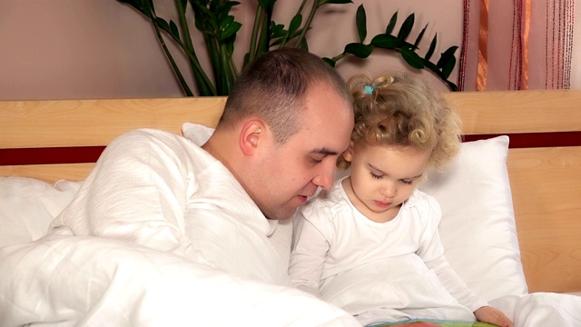 幸福的家庭，爸爸，男人和女儿读故事书的女孩视频素材