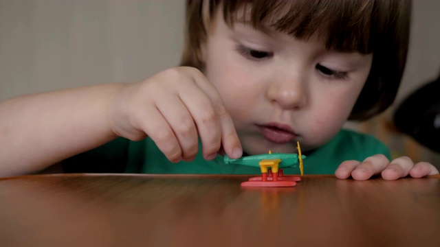 快乐的孩子玩玩具飞机。儿童与飞机旅行玩具的肖像。蹒跚学步的小男孩一边玩着玩具飞机一边做梦。特写镜头。缓慢的运动。视频素材