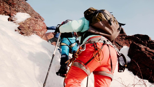 一群训练有素的登山者带着他们的装备试图爬上一个非常陡峭的雪坡视频下载