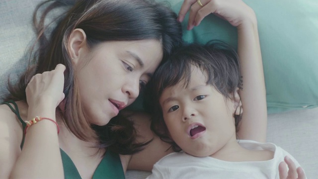 年轻的亚洲母亲和男婴依偎在床上视频素材