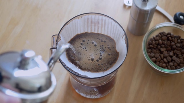 手滴咖啡师将热水倒在咖啡地上桌面视图视频素材
