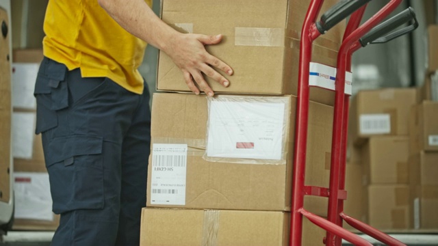男性快递员将包裹从货车上放到手推车上视频下载