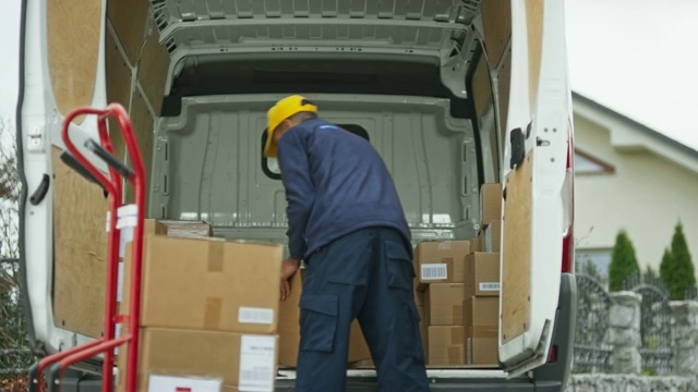 男快递员将包裹从货车上放到手推车上视频下载