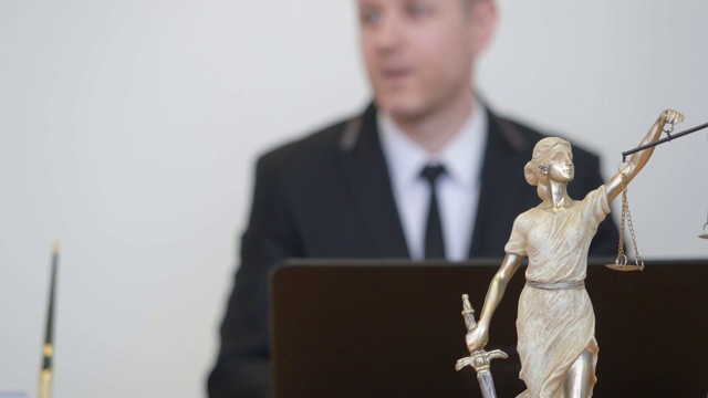 男人和女人咨询专业律师。忒弥斯雕像在律师事务所视频下载