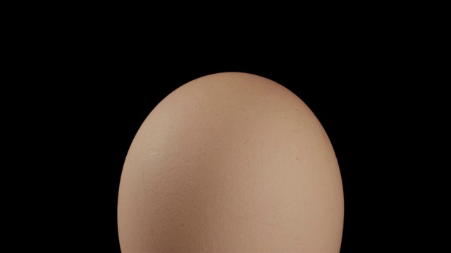 特写，整个棕色的鸡蛋在旋转表面上的黑色背景，直立的位置视频下载