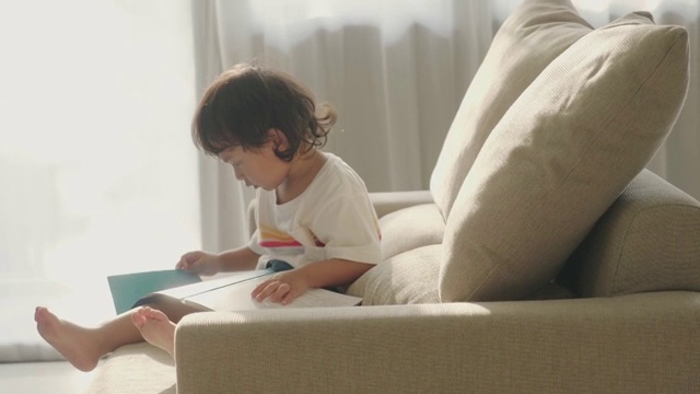 亚洲小男孩在沙发上看书视频素材