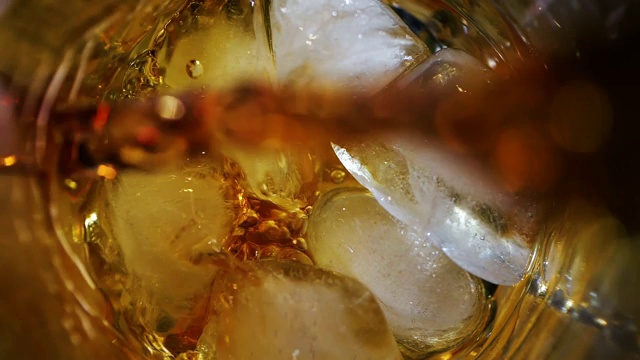 威士忌倒入加冰的玻璃杯中。在黑暗的背景。前视图。视频素材