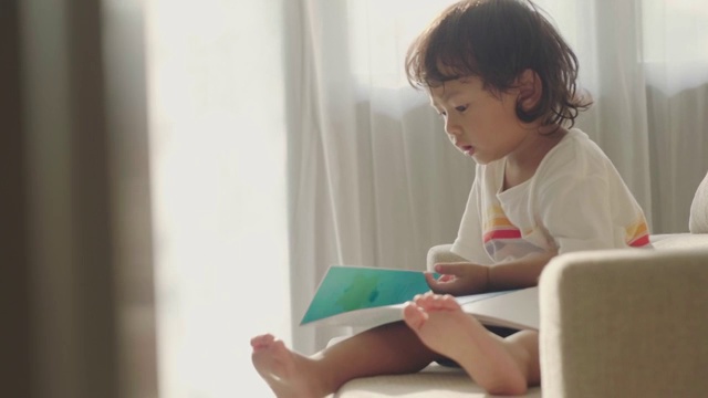 亚洲小男孩在沙发上看书视频素材