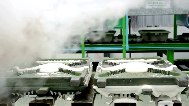 在橡胶枕厂的传送带上，用热蒸汽将金属乳胶枕模具从机器上移出视频素材
