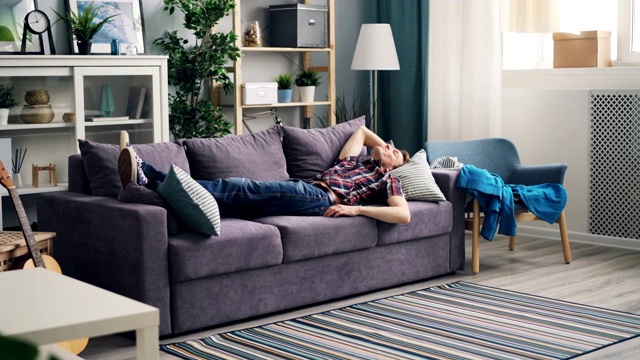疲惫的男人回到家，躺在沙发上放松和享受休息视频素材