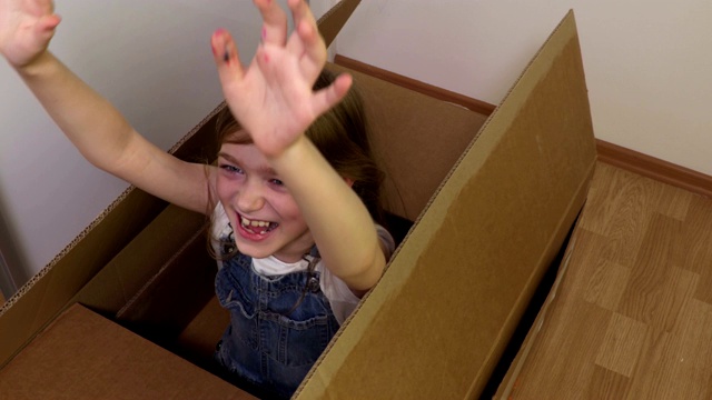 快乐的小女孩试图从纸板箱里出来视频素材