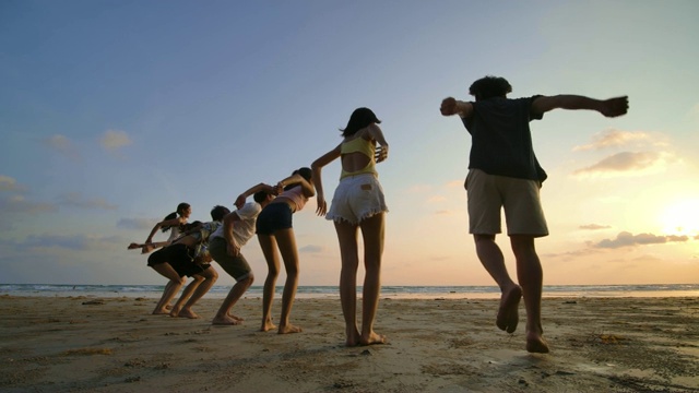 日落时分，朋友们在海滩上跳跃的剪影，心情愉快。4 k决议。慢动作镜头。视频素材