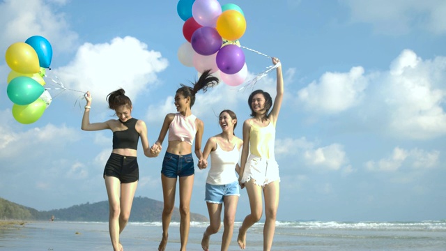 潮人朋友们拿着彩色气球走在海滩上，心情愉快。有聚会庆祝观念的人。4 k决议。慢动作镜头。视频素材