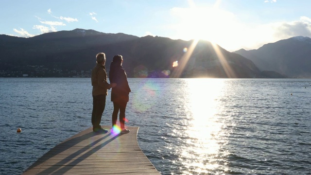 一对夫妇走到湖边码头上，向外眺望视频素材