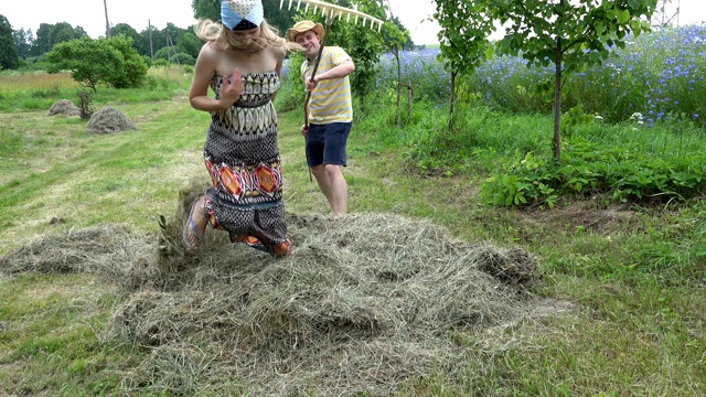 顽皮的农民夫妇和农民在夏天耙干草。4 k视频下载