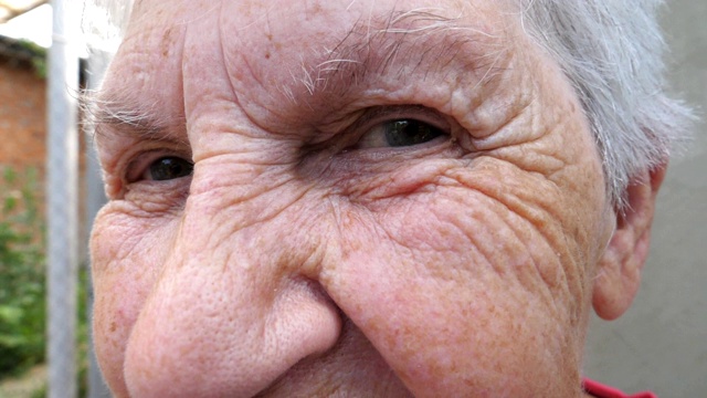 一个快乐的老妇人微笑着看着外面的相机。近距离观察外面满头白发、满脸皱纹的祖母。老奶奶积极的面部表情。慢动作视频素材