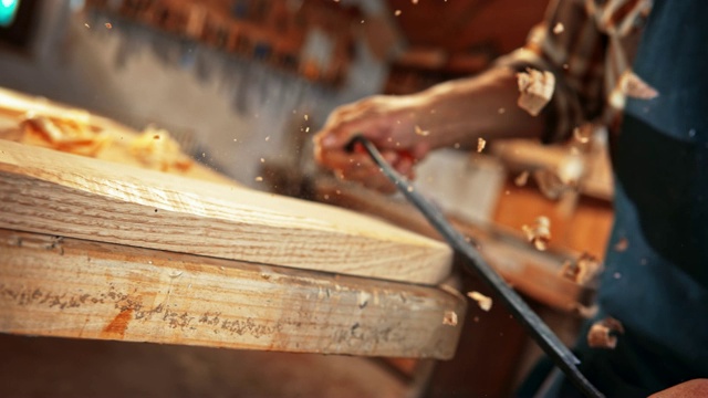 一个男木匠的手拿着一把拔刀，正在修一块木板视频素材