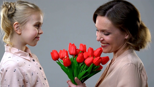 可爱的女孩送花给心爱的母亲，生日或3月8日的惊喜视频素材